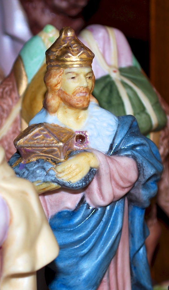 A wise man brings a gift of gold to the holy family.